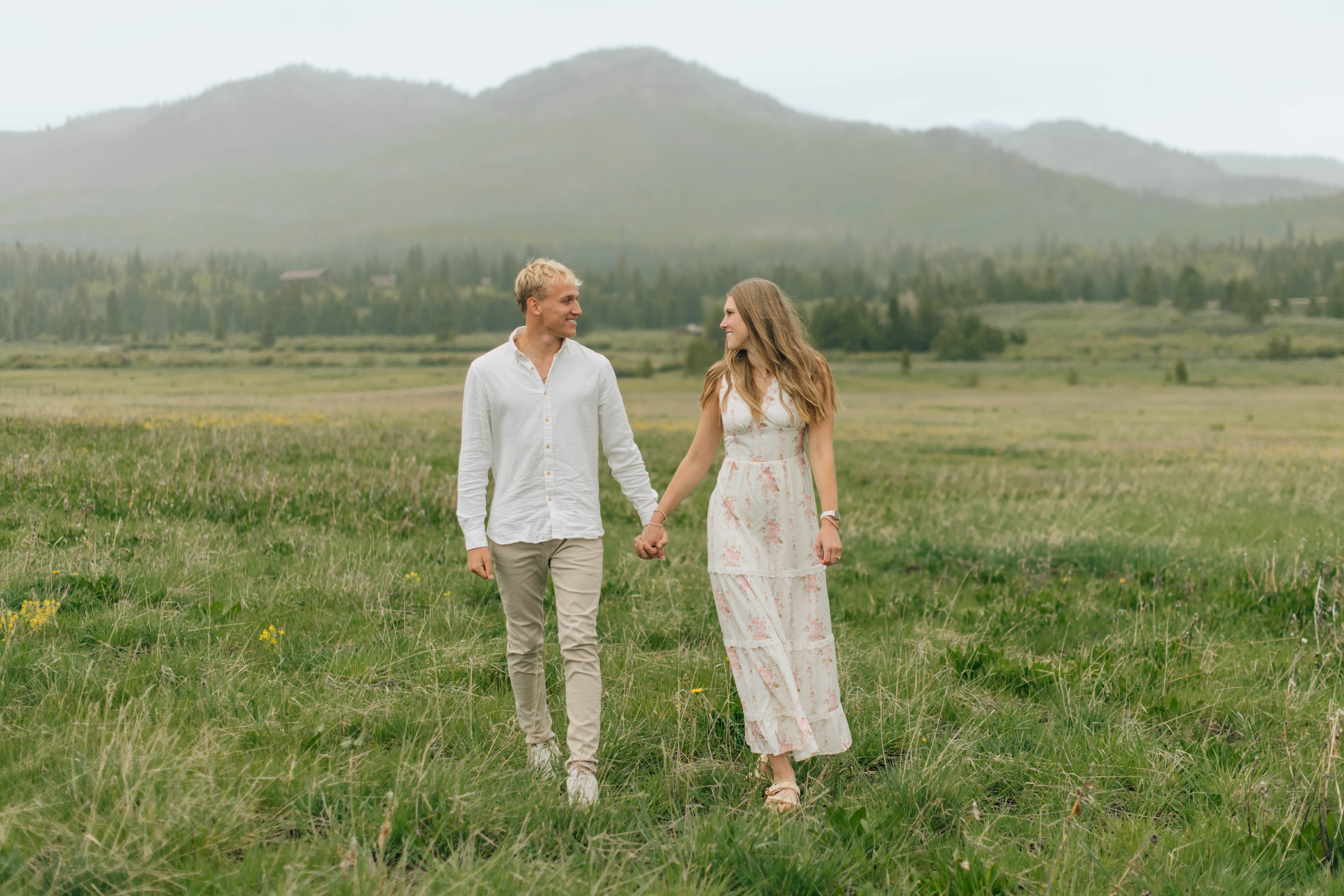 Alyssa and Tysen walking hand in hand through a mountain meadow