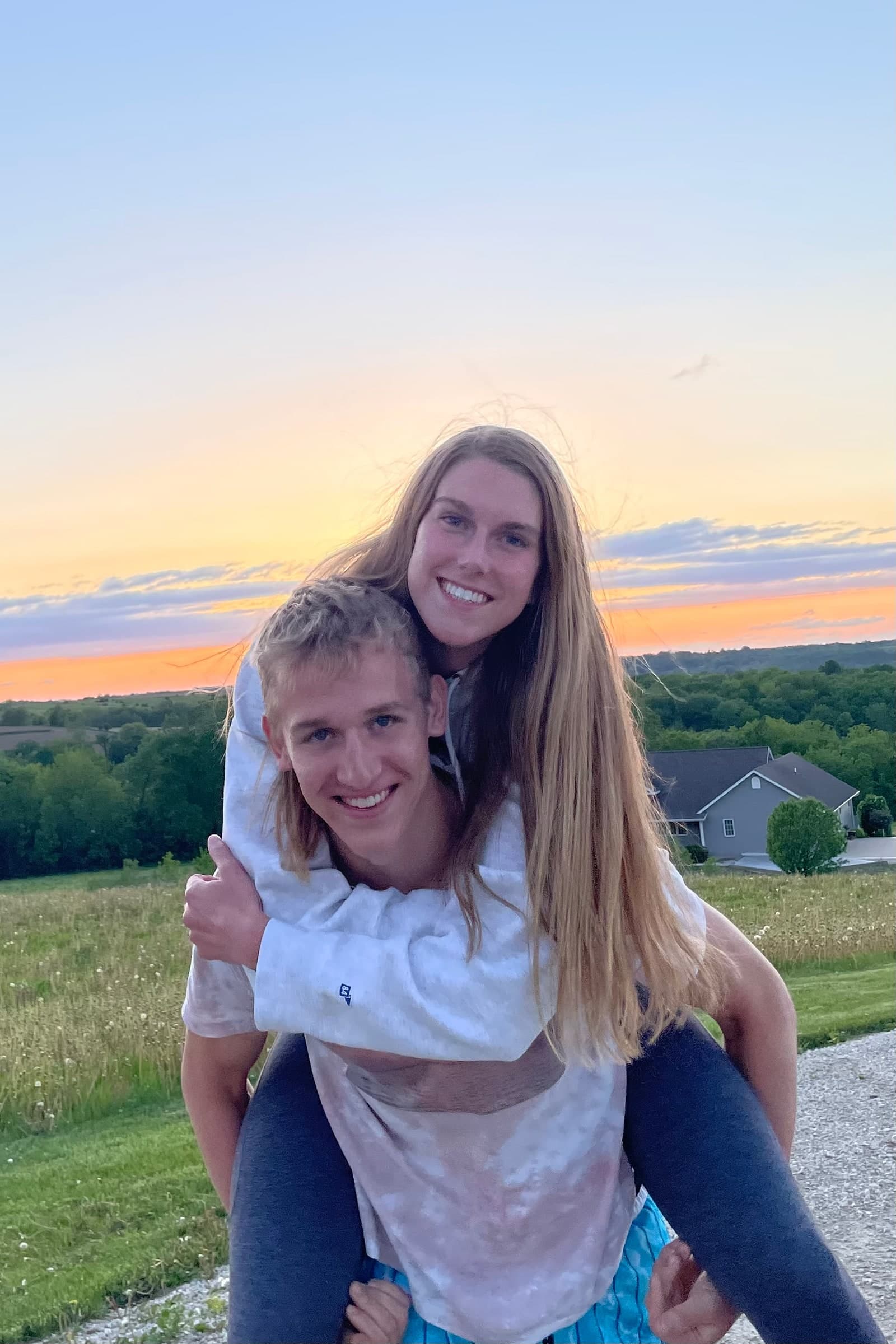 Tysen giving Alyssa a piggyback ride with a sunset behind them