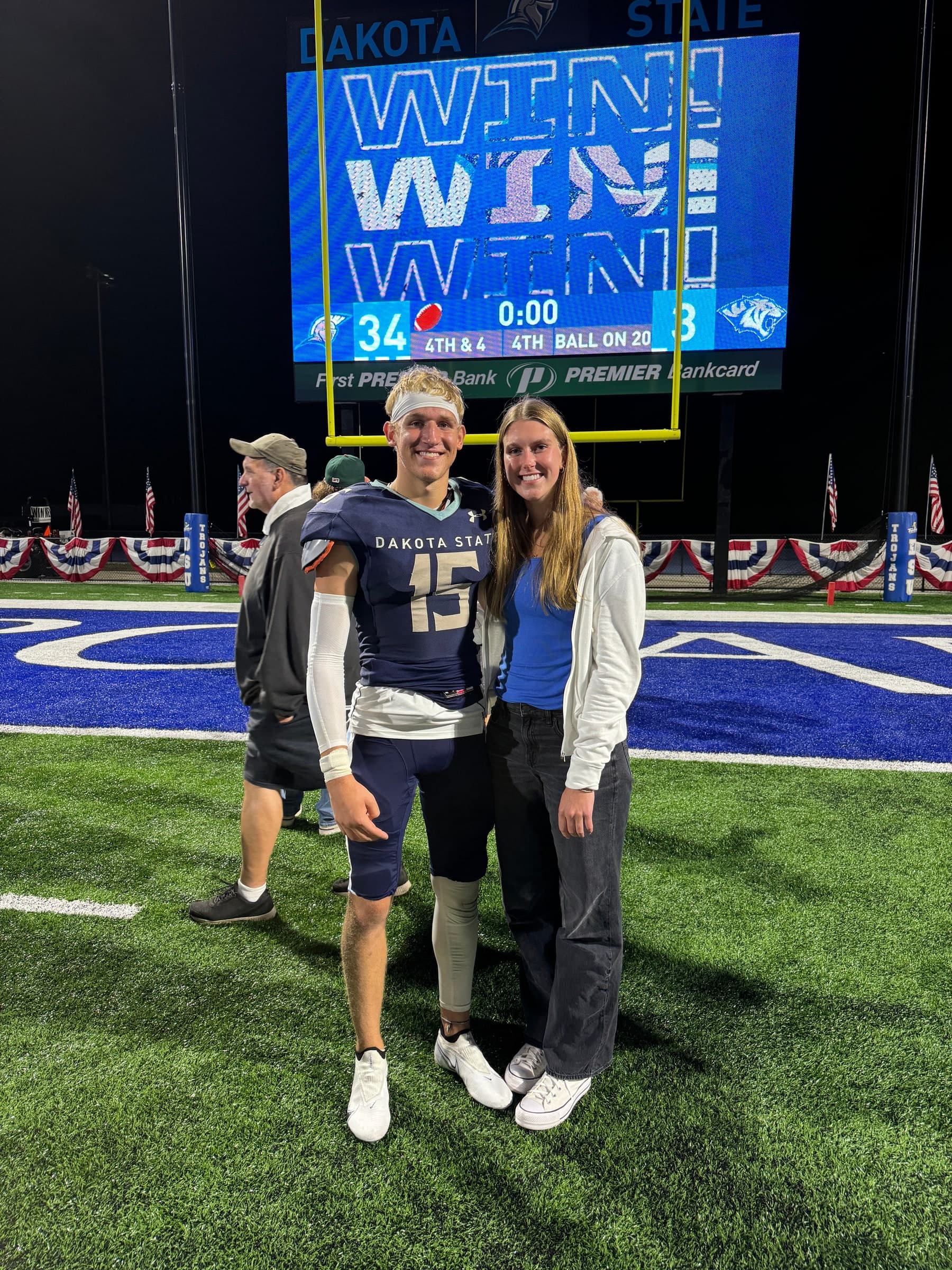 Alyssa beside Tysen in his Dakota State football uniform on the field