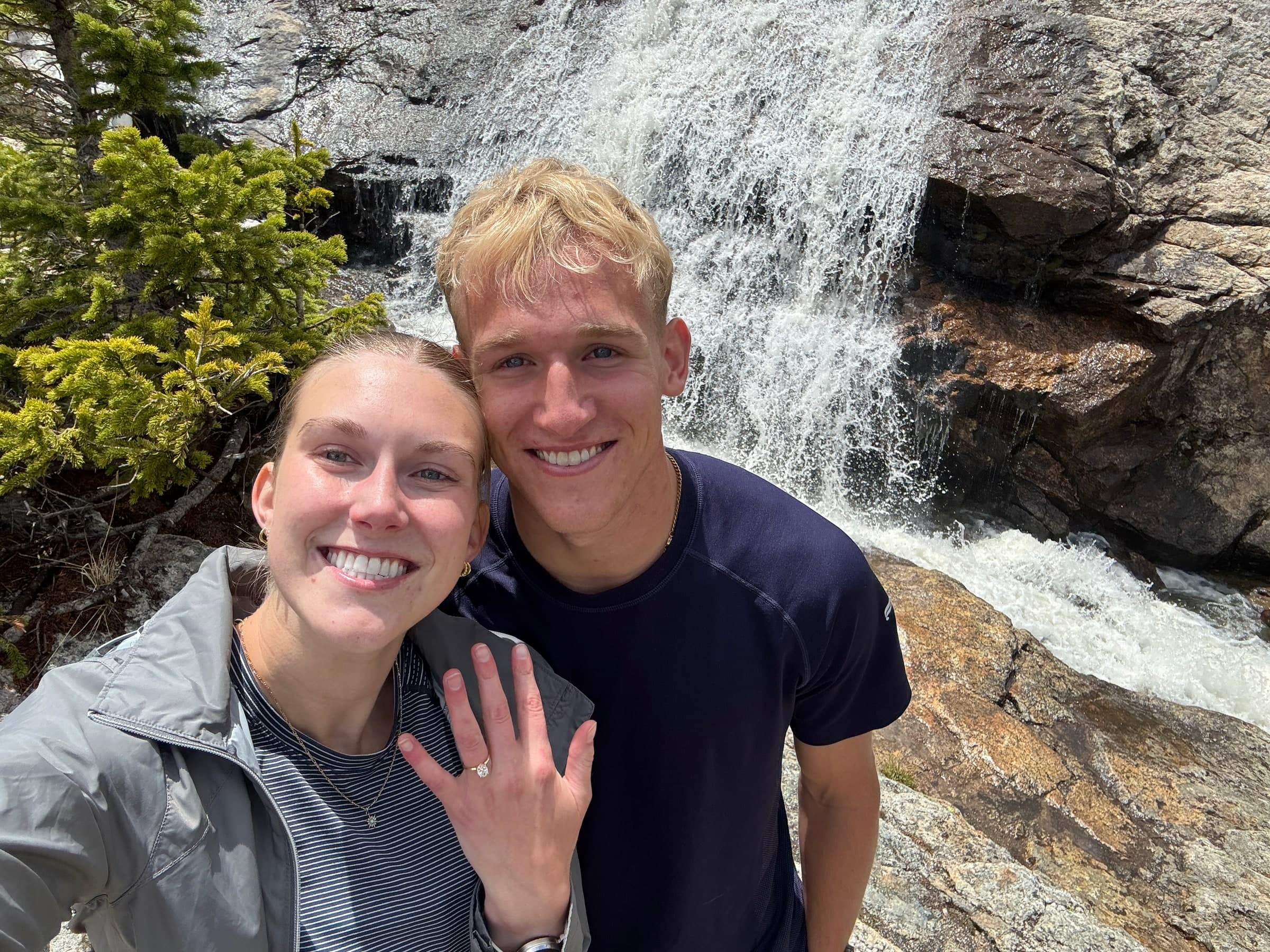 Alyssa and Tysen smiling together beside the waterfall on their Colorado trip