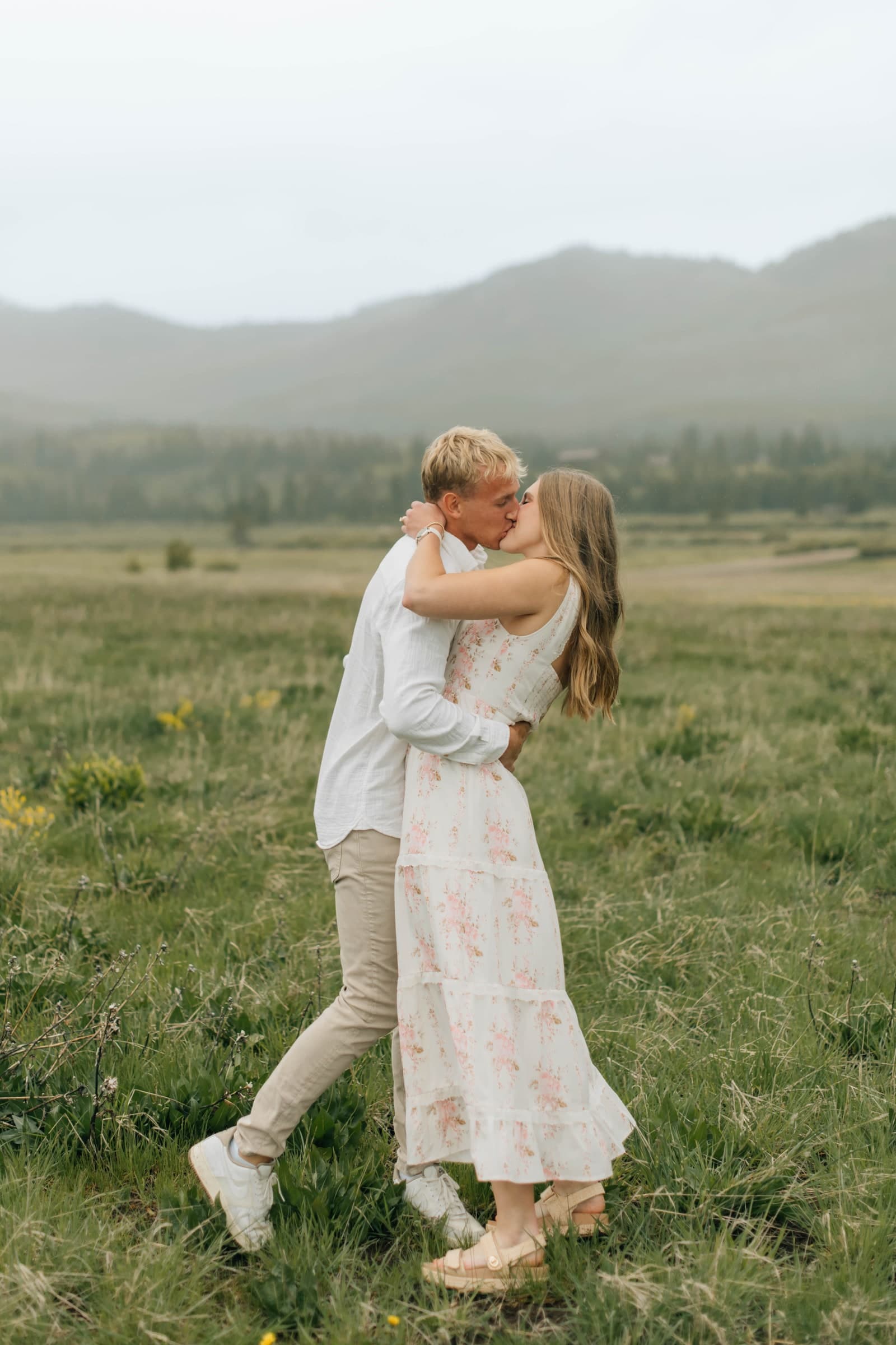 Tysen lifting Alyssa in a meadow during their engagement photography session