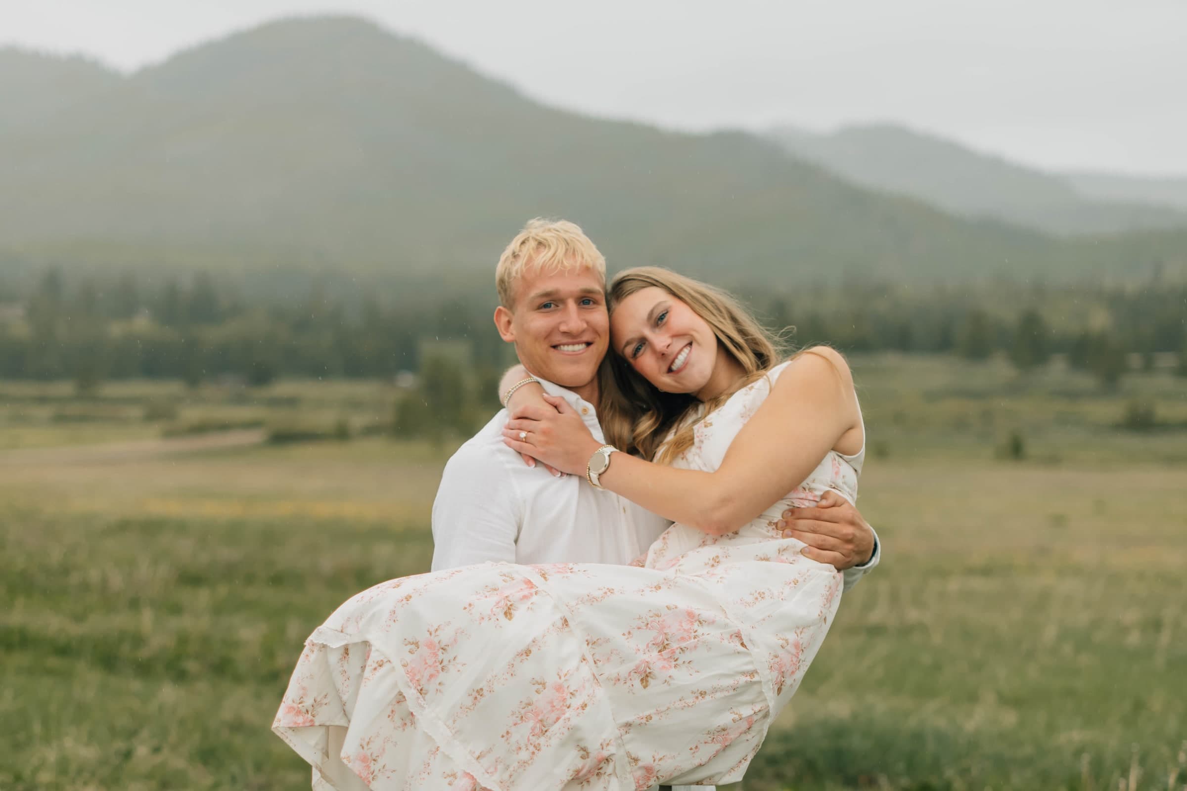 Tysen carrying Alyssa as they smile together in a mountain meadow